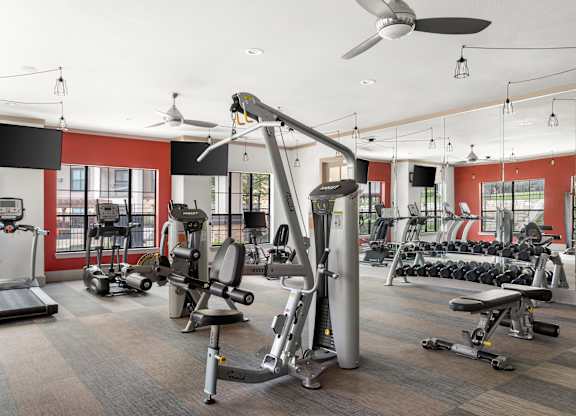 A gym with a variety of equipment including treadmills, weights, and exercise machines.