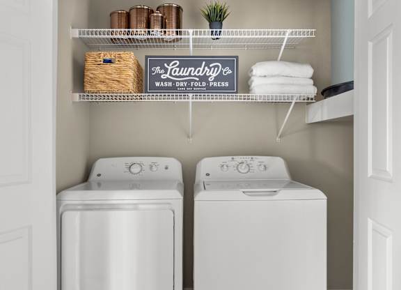 A laundry sign hangs above a shelf with towels and a basket.