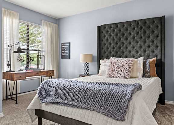 A bedroom with a bed, desk, and chair.
