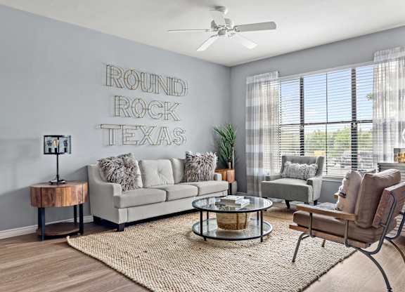 A living room with a couch, chair, and a rug in front of a wall with
