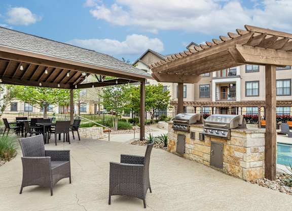 A patio with a table and chairs under a wooden pergola.