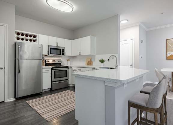 A kitchen with a white counter top and a striped rug on the floor.