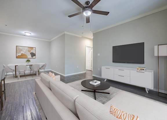 A living room with a couch, a dining table, and a television.