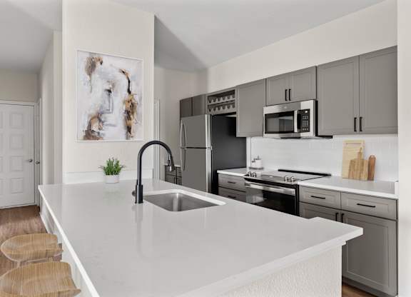A modern kitchen with a white countertop and stainless steel appliances.