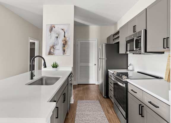 A modern kitchen with a refrigerator, oven, and microwave.