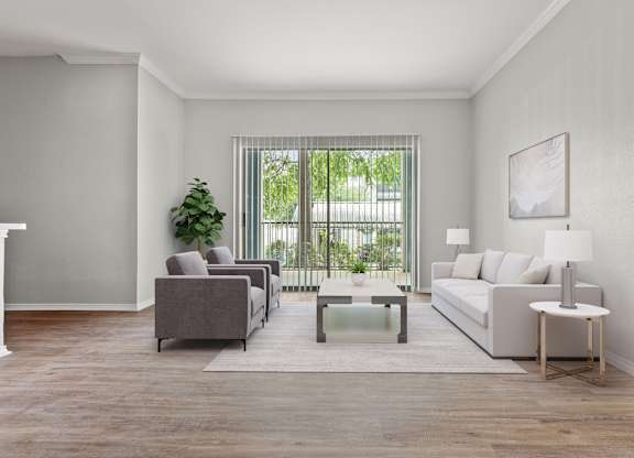 A living room with a grey couch, a grey armchair, a white side table, and a white lamp.