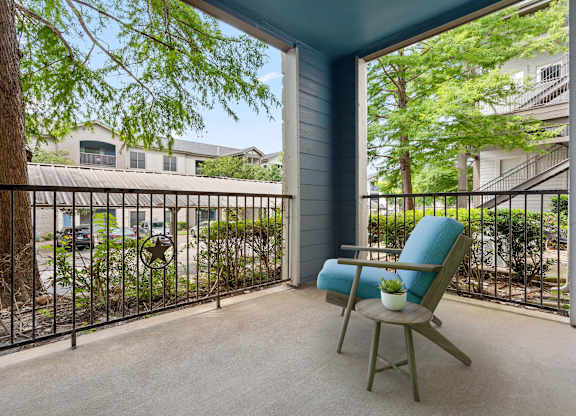A chair sits on a patio with a view of a street and houses.