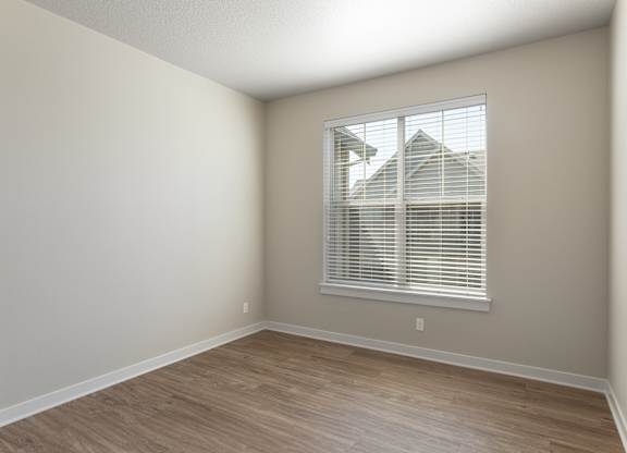 A room with a window and wooden flooring.