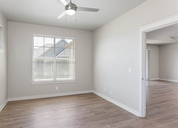 A room with a ceiling fan and a window with blinds.