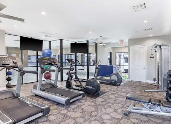 A spacious gym with a variety of equipment including treadmills, elliptical machines, and weight machines.