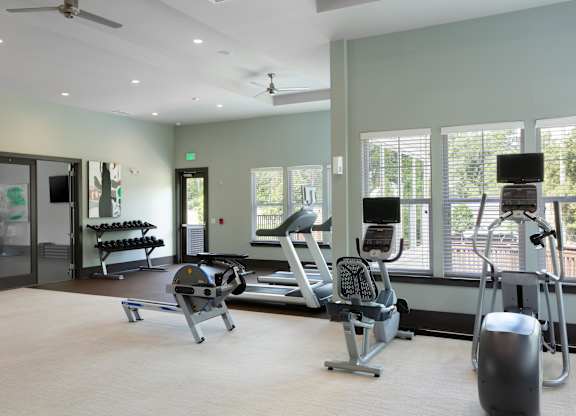 A gym with a variety of equipment including a treadmill, weights, and a bench press.