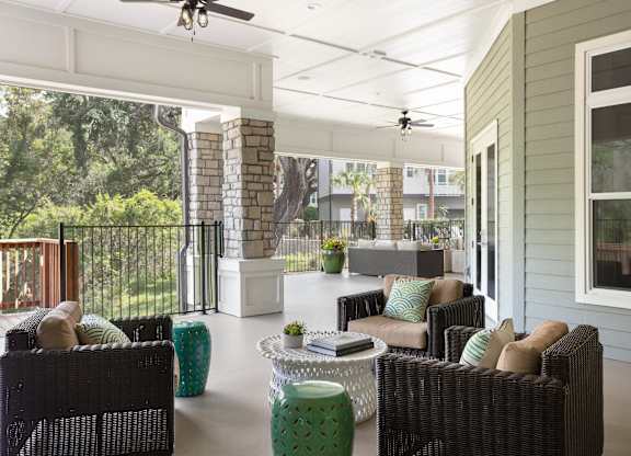 A patio with a black wicker sofa and a white table.