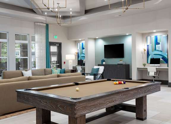 A pool table is in the middle of a room with a couch and a television.