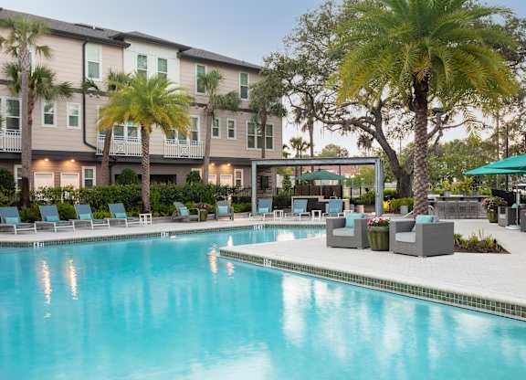 A swimming pool in front of a building with palm trees.
