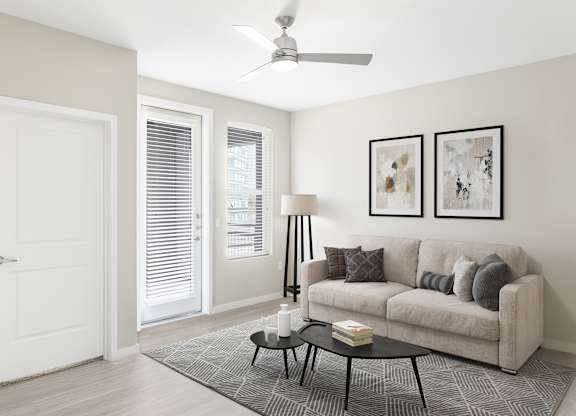 A living room with a couch, a table, and a ceiling fan.