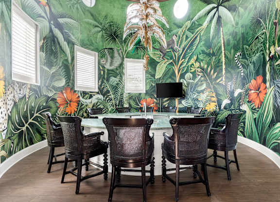 A room with a green wallpaper and a table with chairs.
