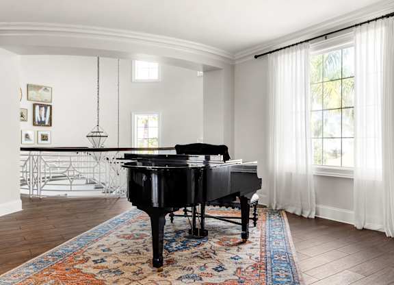A black grand piano sits in a room with a white piano bench.