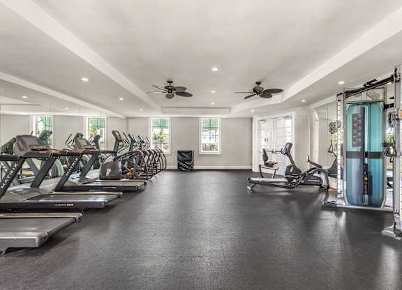 A spacious gym with treadmills, exercise bikes, and weights.