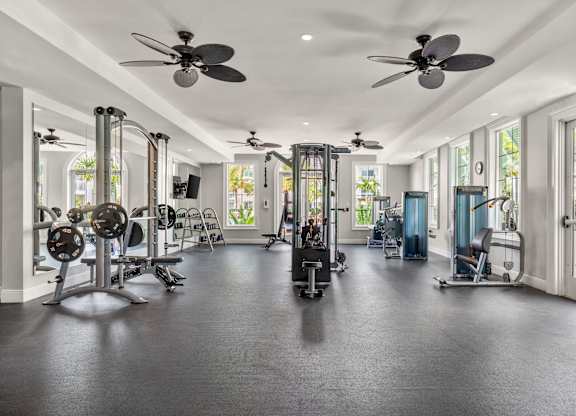 A spacious gym with a variety of equipment and a ceiling fan.