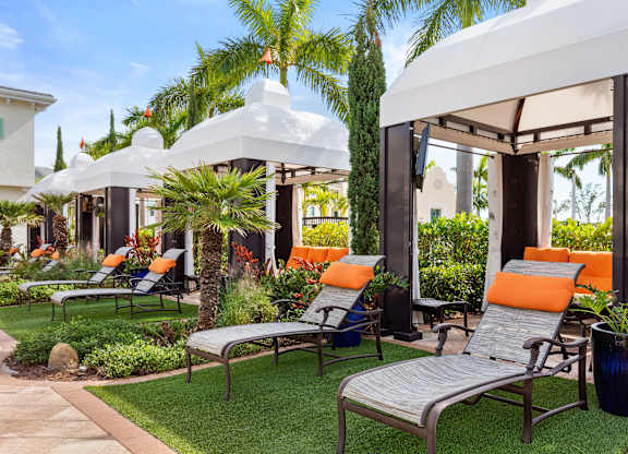 A white gazebo is surrounded by lawn chairs and plants.