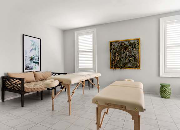 A room with a massage table, a couch, and a painting on the wall.