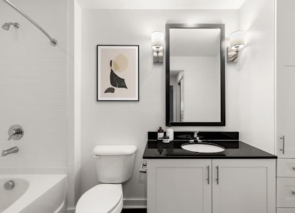 A bathroom with a white toilet, sink, and a framed picture on the wall.