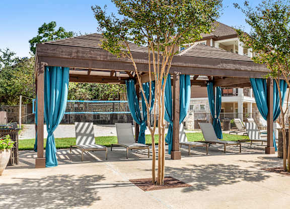 A patio with a gazebo and chairs.