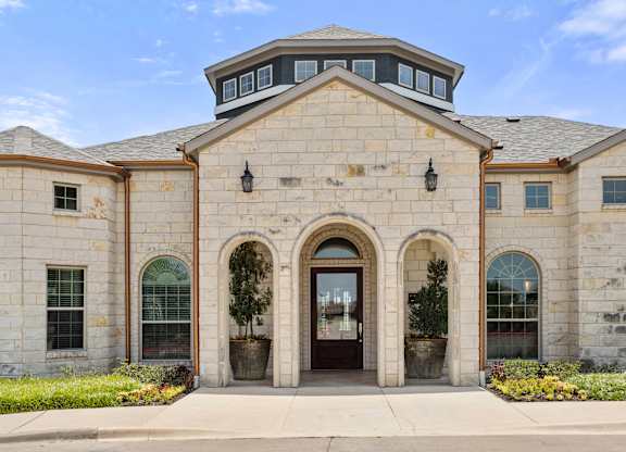 A stone building with a large arched entrance and a round window above it.