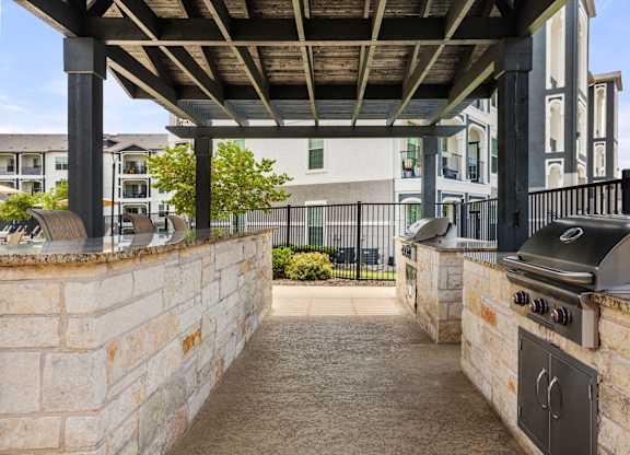 A patio with a grill and a stone wall.