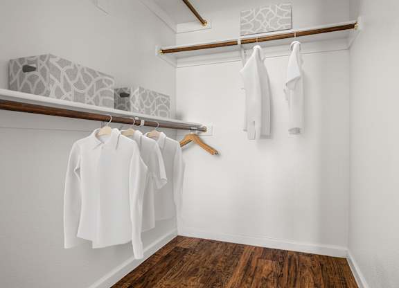 A row of white shirts hanging on a rack in a room.