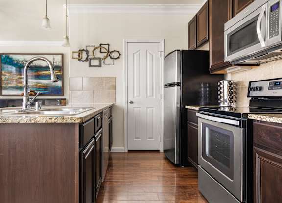 A kitchen with dark wood cabinets and black appliances.
