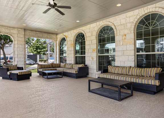 A patio with a striped couch and a ceiling fan.