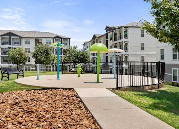 A playground area with a slide, swing set, and a green umbrella.