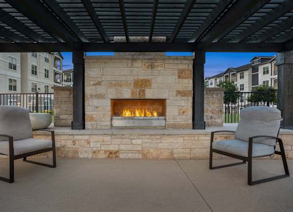 Two chairs are placed in front of a stone fireplace.