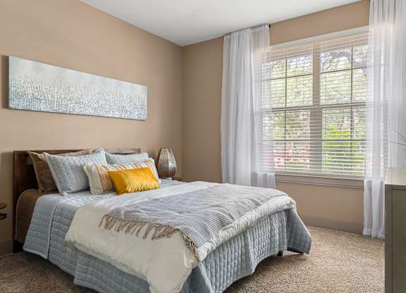 A bedroom with a bed, a chair, and a painting on the wall.