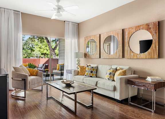 A living room with a white couch and a glass coffee table.