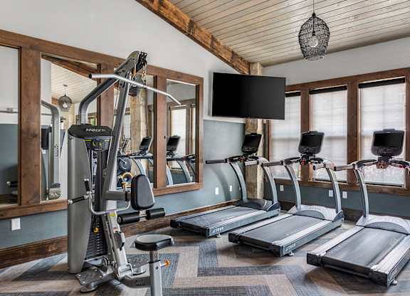 A home gym with treadmills, a stationary bike, and a mirror.