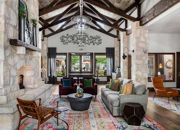 A living room with a stone fireplace and a large chandelier.