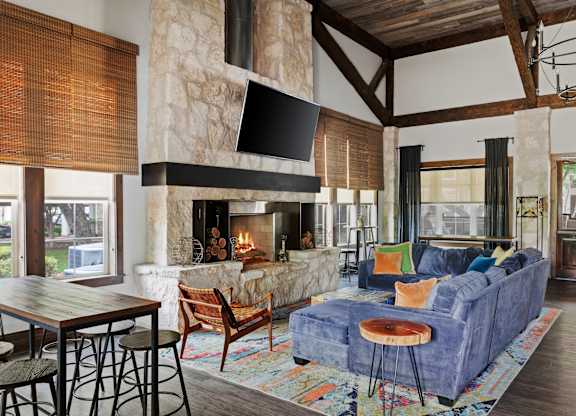 A living room with a stone fireplace and a blue couch.