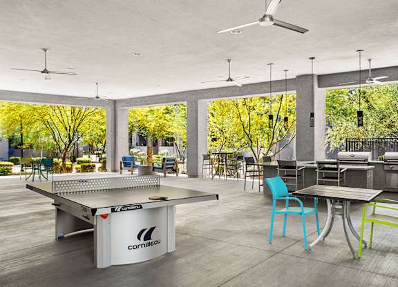 A ping pong table is in the middle of a room with a table and chairs.