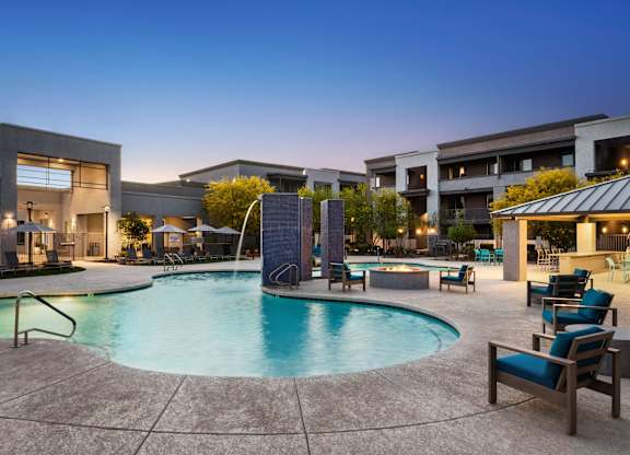 A swimming pool surrounded by lounge chairs and a building in the background.