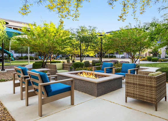 A patio with a fire pit and chairs.