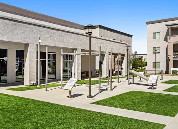 A modern building with a glass entrance and a green lawn in front.