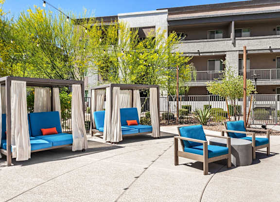 Four blue chairs are arranged in a row under four canopies.