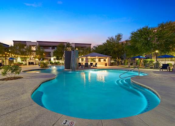 A swimming pool in a resort with a building in the background.