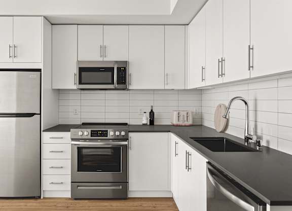 A modern kitchen with a stainless steel refrigerator, oven, and microwave.