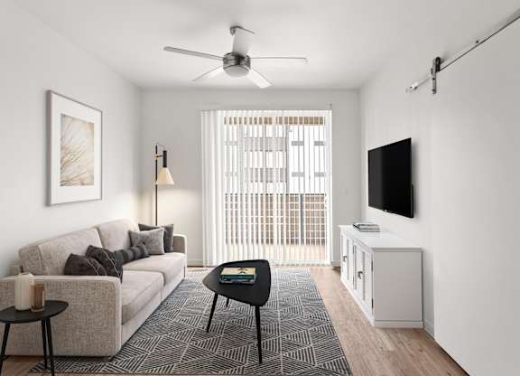 A living room with a couch, a table, a television, and a window with blinds.