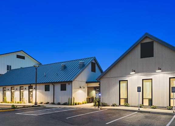 A building with a blue roof and white walls with a parking lot in front.