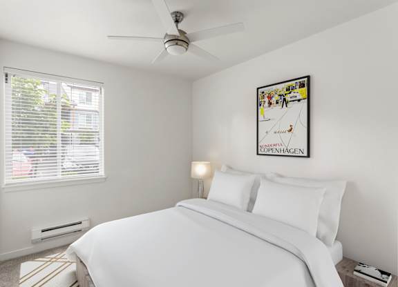 A bedroom with a bed, a ceiling fan, and a picture on the wall.