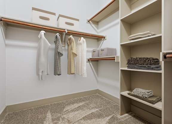 A white and beige laundry room with clothes hanging and folded on shelves.